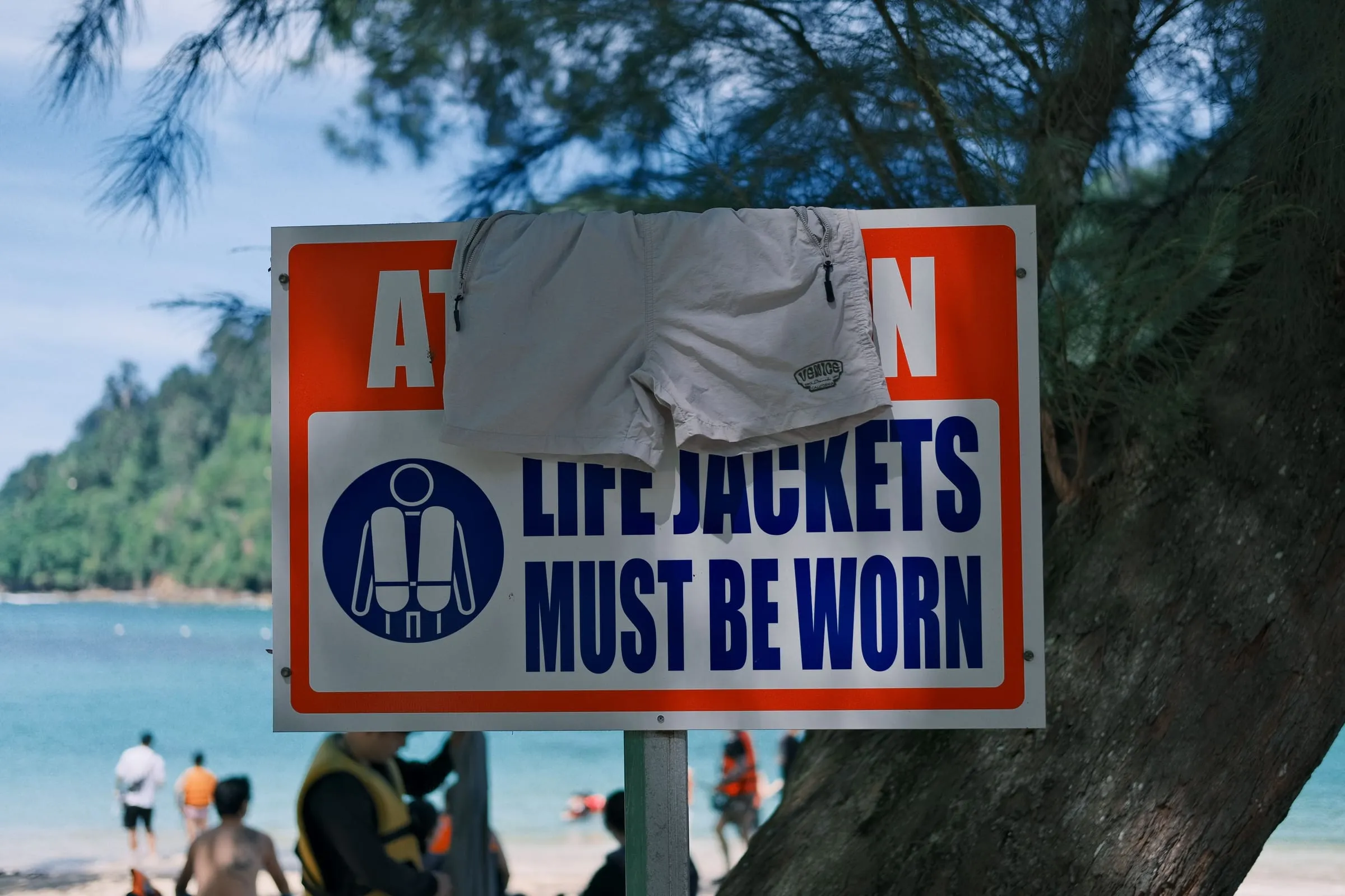 A waterfront sign reading 'Life jackets must be worn,' with a life-jacket icon